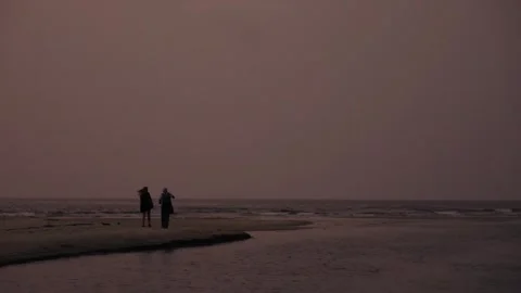 Couple walking on a desolate beach at dusk Video stock 345897154