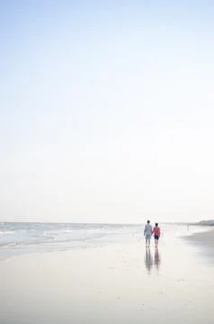 A couple walking down the beach. Stock Photos