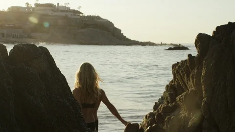 Couple walking down rocks towards sea on a sunny day Stock Footage 106324173
