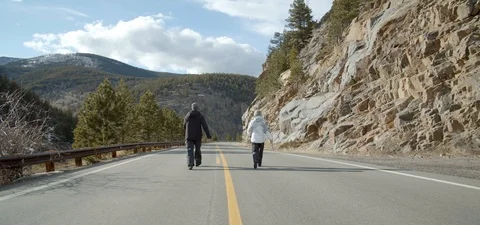 Couple Walking Down Winding Mountain Road, Rocky Mountains Stock Footage 109489473