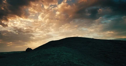 Couple walking in far distance on volcano mountain under a dramatic sky Stock-Footage 72948933