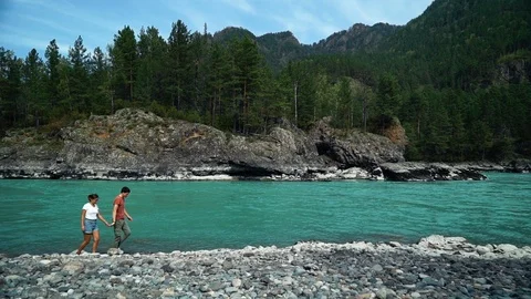 Couple walking by the fast mountain river. Long shot 库存影片 97404535