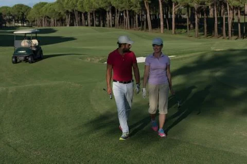 Couple walking on golf course Fotos de archivo