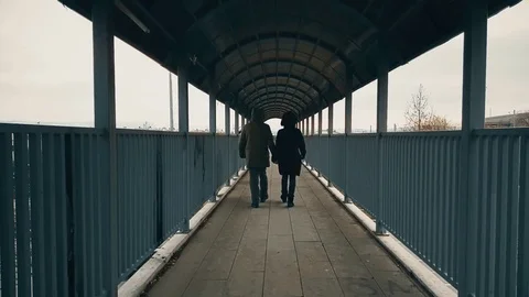 Couple walking hand-to-hand across the footbridge over highway Stock Footage 78347271