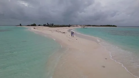 Couple walking hand in hand along a serene white sandbar in Los Roques paradise 스톡 동영상 340846825