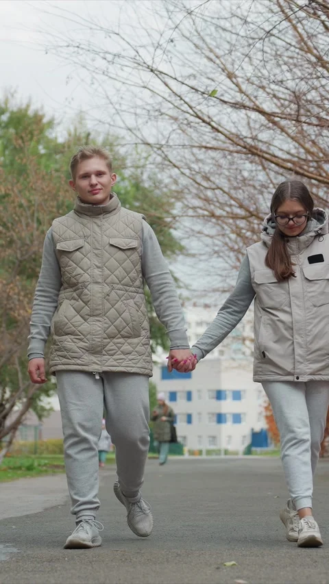 Couple Walking Hand in Hand on Paved Pathway Wearing Matching Beige Vests and Stock Footage 342733259