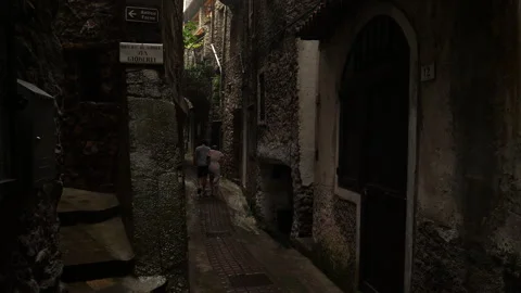 Couple walking in heavy rain down alley in small Italian village. Stock Footage 141188177