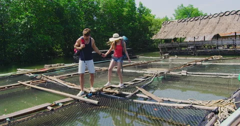 Couple walking on net walkways on fish farm tour in Asia Thailand. Summer holida Stock Footage 201095296