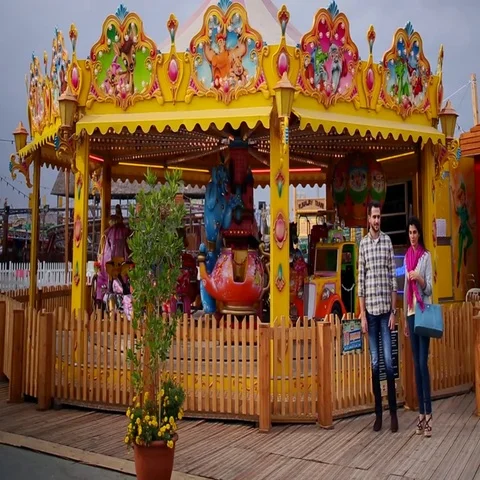 Couple walking next to carousel at funfair, Dubai, United Arab Emirates. Vídeo Stock 69483739