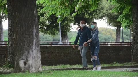 Couple walking in a park wearing medical masks due to Covid-19 pandemic Stock Footage