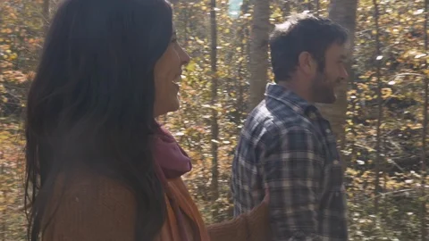 Couple walking past the camera holding hands enjoying a hike through the woods Stock Footage 101445381