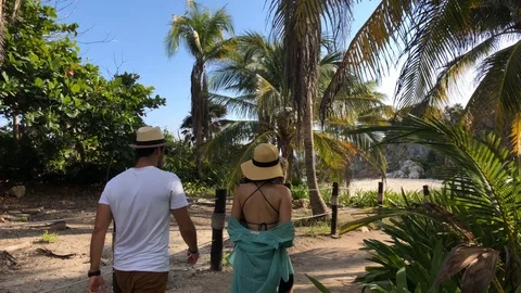 Couple Walking Up Path Along Coast of Tulum Mexico Tracking Shot Video stock 90012243