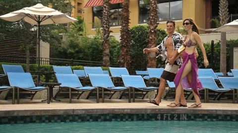 Couple walking by resort pool Stock Footage 33046791