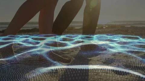 Couple walking on shore, stepping into blue mesh revealing footprints for Stock Footage 331701013