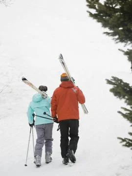 Couple walking with skis over shoulders Fotos Stock