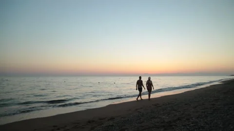 Couple walking at sunset on the beach Stock Footage 68668696