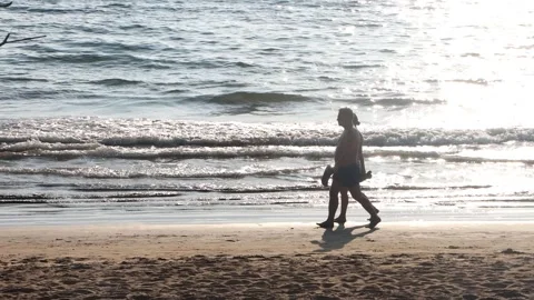 Couple walking at sunset on the beach with sun reflection Stock Footage 342278051