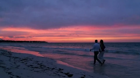 Couple Walking Through Ocean Waves on Beach, Romantic Sunset Stock Footage