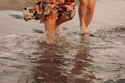 Couple Walking Through Ocean Waves in Beach Stock Photos