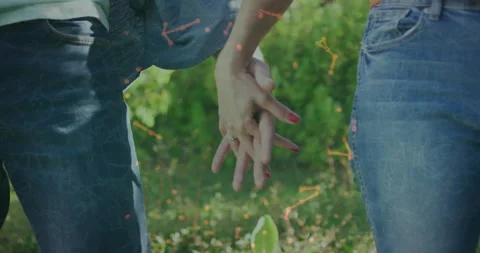 Couple walking through park bringing hands together and interlocking fingers Video stock 312019033
