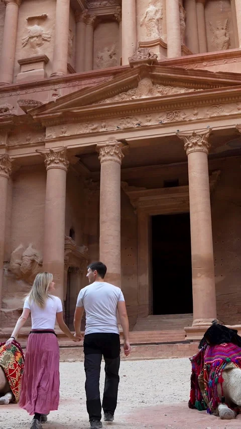 Couple walking to the Treasury in Petra with resting camels Stock Footage 346798050