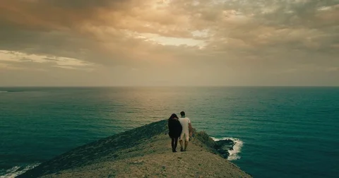A couple walking on a volcano peninsula overlooking the Atlantic ocean Stock Footage 72949412