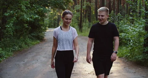 The couple walks after jogging through the woods. A man and a woman are walking Stock Footage 210871509