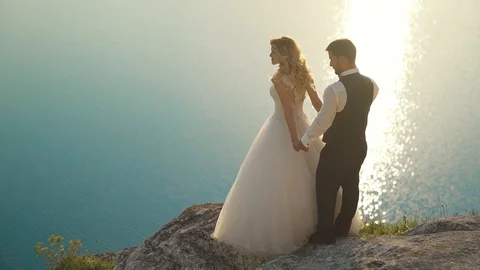 Couple walks out to ocean cliffs, takes in view together. Slow motion. Stock Footage 107809725