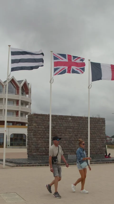 Couple Walks Past Flags at Dunkirk Seaside Memorial Stock Footage 323159583