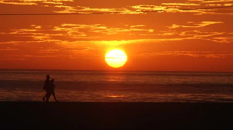 Couple walks by at sunset on the beach Video stock 1092085