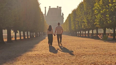 Couple walks through a sunlit tree-lined garden in Paris France Stock-Footage 348650745