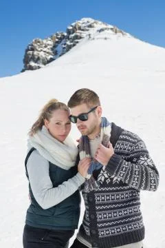 Couple in warm clothing in front of snowed hill Stock Photos