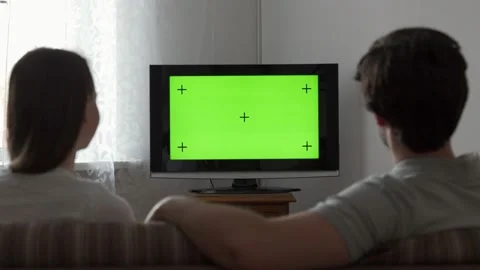 Couple watches green mock-up screen tv while sitting on a couch in the living Stock Footage 150827853