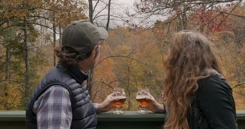 Couple watching the leaves fall off the trees from a deck in the autumn Stock Footage 112229935