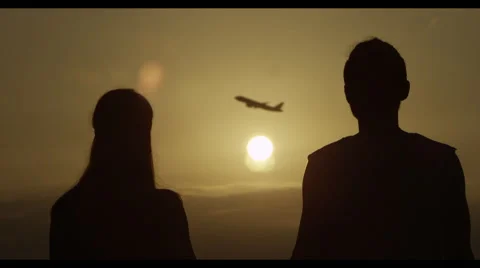 Couple watching plane fly across a sunset Stock Footage 51714892