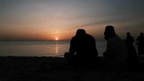 Couple watching sunset on the beach Stock Footage 250332373