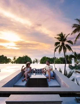 Couple watching sunset in infinity pool on a luxury vacation in Thailand Stock Photos