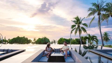 Couple watching the sunset in an infinity pool on a luxury vacation in Thaila Stock Photos