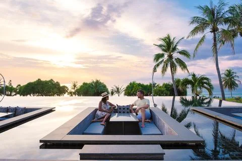 Couple watching the sunset in an infinity pool on a luxury vacation in Thaila Stock Photos