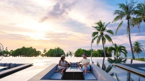 Couple watching the sunset in an infinity pool on a luxury vacation in Tha... Stock Photos