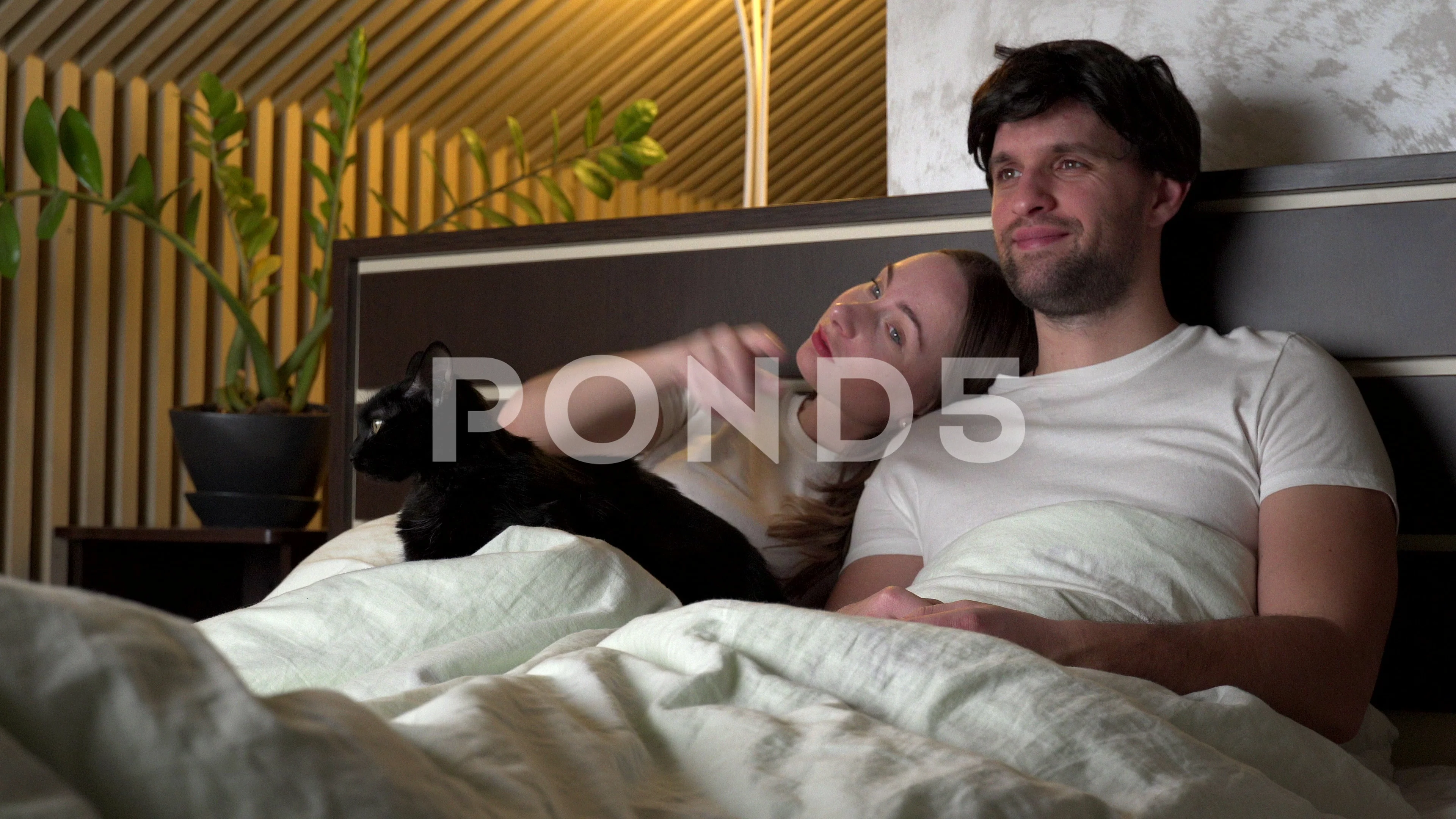 Couple watching TV at night at home lying on the bed