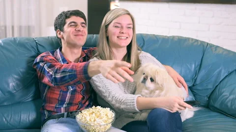 Couple watching tv program sitting on a couch Stock Footage 60823068