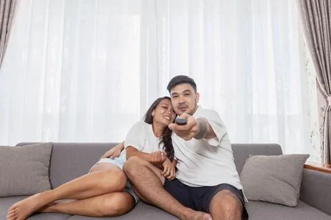 Couple watching tv while sitting on sofa at home. Concept of Stay at home dur Stock Photos