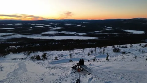Couple watching winter sunset from Levi fell, Lapland, aerial drone pan shot Stock Footage 301302933