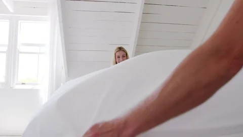 Couple Wearing Pajamas Making Bed In Morning Stock Footage