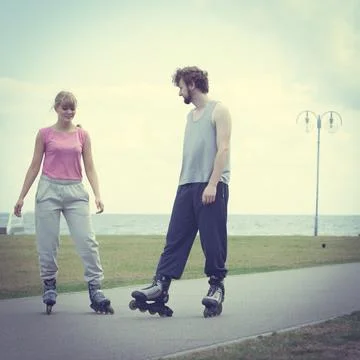 Couple wearing rollerskates looking at each other Stock Photos