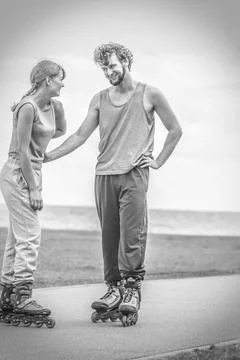 Couple wearing rollerskates looking at each other Stock Photos