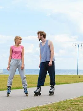 Couple wearing rollerskates looking at each other Stock Photos