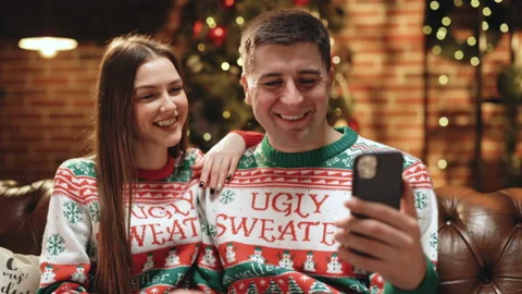 Couple in winter sweaters record video of New Year's greetings for friends and Stock Footage 194593093
