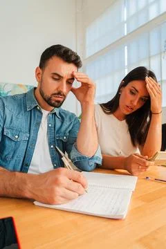 Couple at a wooden table writing notes in a notebook during a focused study Stock Photos